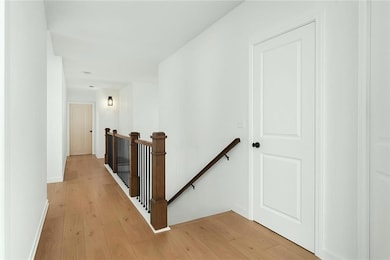 Hallway featuring light wood-style flooring, baseb