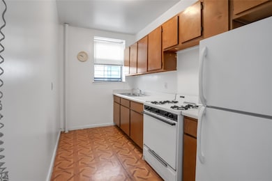 Kitchen with baseboards, light countertops, brown cabinets, white appliances, and a sink