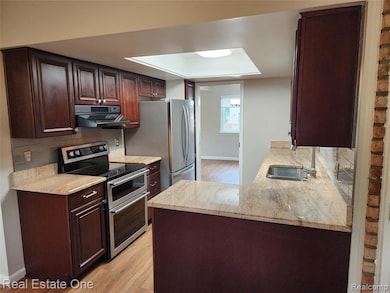 Kitchen featuring stainless steel appliances, tasteful backsplash, and light wood-style floors