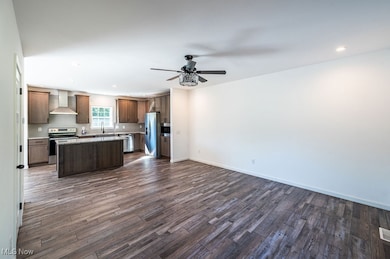 Kitchen with open floor plan, a center island, recessed lighting, appliances with stainless steel finishes, and dark wood finished floors