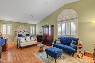 Bedroom with light wood-type flooring, multiple windows, high vaulted ceiling, and a ceiling fan