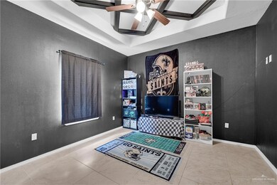 Recreation room featuring a tray ceiling, baseboards, tile patterned flooring, and a ceiling fan