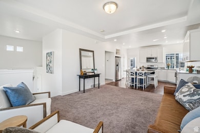 Living area with dark carpet, recessed lighting, and a raised ceiling