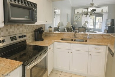 Kitchen with appliances with stainless steel finishes, light stone countertops, white cabinetry, pendant lighting, and ornamental molding