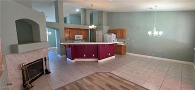 Kitchen with a chandelier, light tile patterned floors, brown cabinetry, a breakfast bar, and white appliances