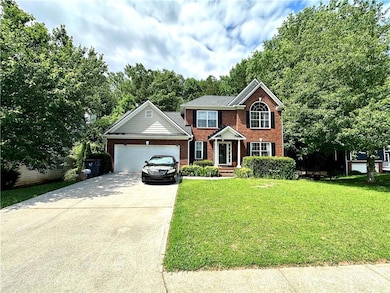 Colonial inspired home with brick siding, an attached garage, concrete driveway, and a front lawn
