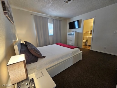 Carpeted bedroom with a textured ceiling and ensuite bath