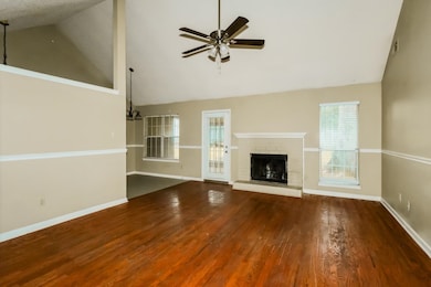 Unfurnished living room featuring high vaulted ceiling, a fireplace, dark wood-style flooring, and ceiling fan