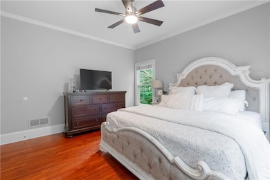 Bedroom with wood finished floors, baseboards, crown molding, and a ceiling fan