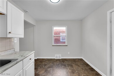 Kitchen with white cabinetry, light countertops, stone finish flooring, and backsplash