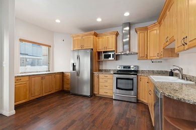 Kitchen featuring appliances with stainless steel finishes, wall chimney exhaust hood, open shelves, recessed lighting, and dark wood-style flooring