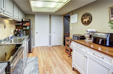 Kitchen featuring electric stove, tasteful backsplash, wooden counters, sink, and light wood-type flooring