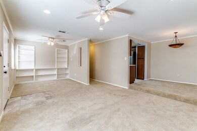 Unfurnished living room featuring light carpet, crown molding, ceiling fan, built in shelves, and recessed lighting