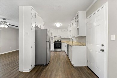 Kitchen with white cabinets, open shelves, appliances with stainless steel finishes, and dark wood-style floors