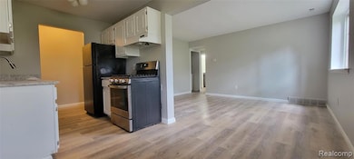 Kitchen with white cabinets, gas range, light wood-style flooring, and under cabinet range hood
