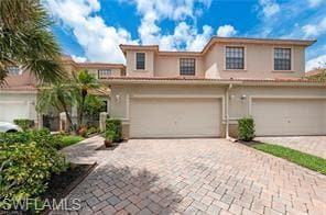 View of front facade featuring decorative driveway, stucco siding, and an attached garage