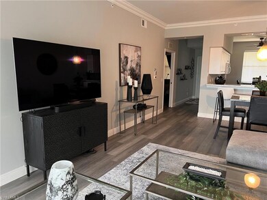 Living room with crown molding, dark wood-type flo