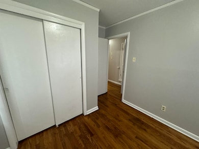 Unfurnished bedroom featuring a closet, dark hardwood / wood-style flooring, and crown molding