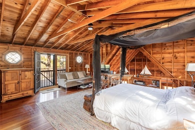 Bedroom with wooden walls, wooden ceiling, wood finished floors, and access to exterior