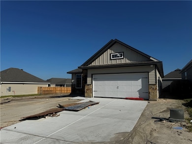 View of front facade with board and batten siding, stone siding, a garage, and driveway