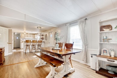 Dining area with light wood-style floors, vaulted 