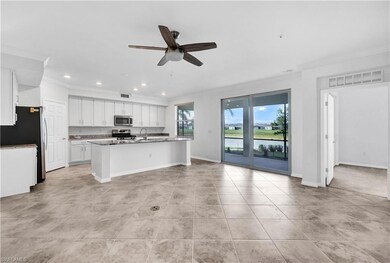 Kitchen featuring white cabinets, an island with sink, and light tile floors