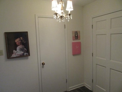 Hall featuring baseboards and a chandelier