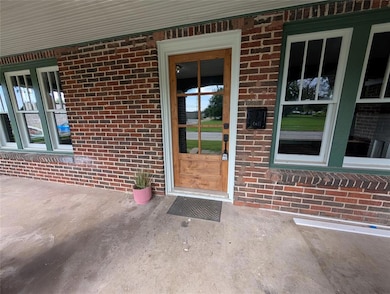 Doorway to property featuring uncovered parking and brick siding