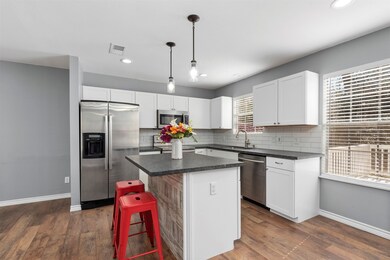 Featuring a kitchen island with breakfast bar, pendant fixture lighting, and light and bright white cabinetry, the kitchen is a chef's delight.