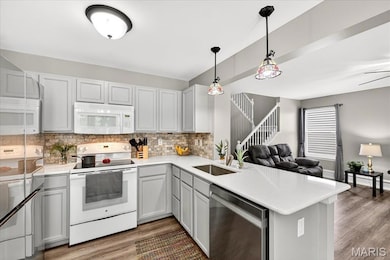 Kitchen with open floor plan, stainless steel appliances, backsplash, solid surface countertops, and wood finished floors
