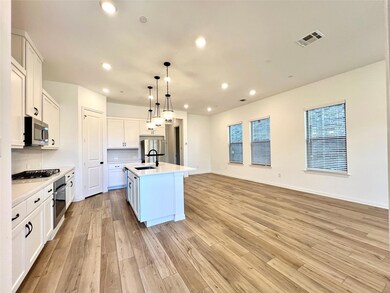 Kitchen with visible vents, stainless steel appliances, light countertops, white cabinetry, and light wood-type flooring