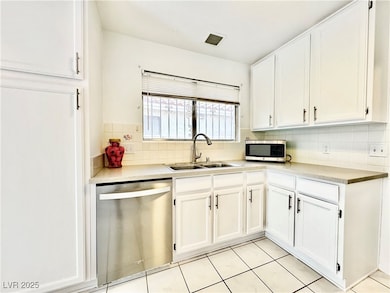 Kitchen with white cabinets, appliances with stainless steel finishes, tasteful backsplash, and light countertops