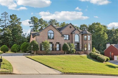View of front of property with brick siding, a front lawn, and view of wooded area