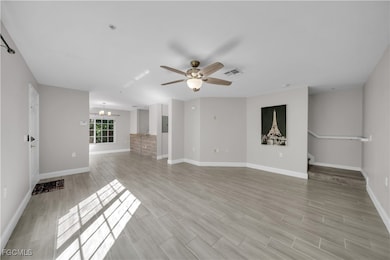 Unfurnished living room featuring wood finish floors, ceiling fan, and a chandelier