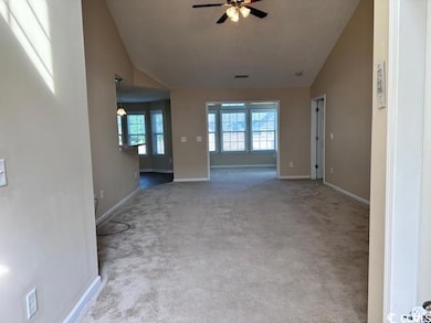 Unfurnished living room with ceiling fan, carpet flooring, and vaulted ceiling