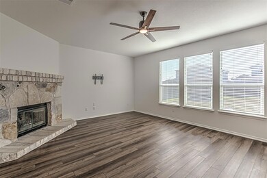 Unfurnished living room with ceiling fan, dark wood finished floors, and a stone fireplace