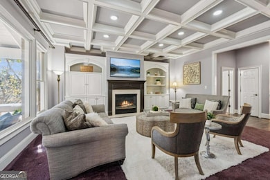 Expansive family room featuring detailed coffered ceilings, built-in cabinetry, and a warm fireplace focal point.