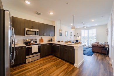 Kitchen with stainless steel appliances, light countertops, visible vents, a sink, and open floor plan