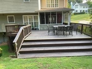 Rear view of property with a deck, outdoor dining space, and a yard