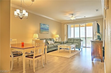 Living area featuring crown molding, light wood-style floors, ceiling fan, and a chandelier