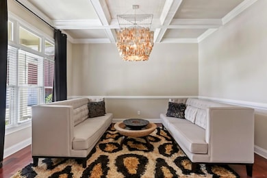 Sitting room with coffered ceiling, a chandelier, wood finished floors, baseboards, and beamed ceiling
