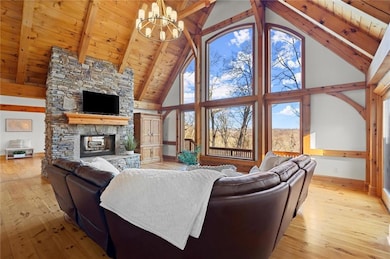Living room with high vaulted ceiling, a chandelier, baseboards, light wood-style flooring, and beamed ceiling
