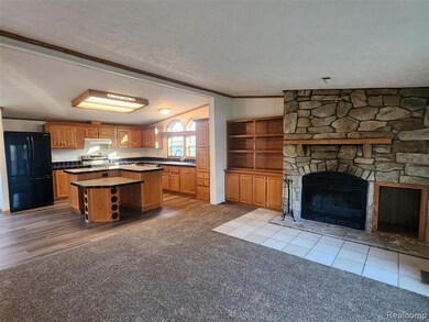 Kitchen with freestanding refrigerator, vaulted ceiling, a center island, light carpet, and a textured ceiling