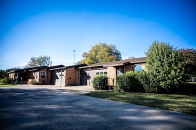 View of front of home with brick siding, concrete driveway, a front lawn, and a garage