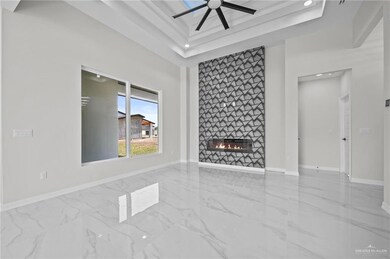 Unfurnished living room with a tray ceiling, marble finish floor, a large fireplace, and baseboards