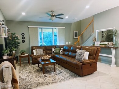Tiled living area with stairway, a ceiling fan, an