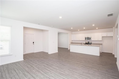 Kitchen featuring stainless steel appliances, light wood finished floors, white cabinetry, recessed lighting, and open floor plan
