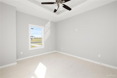 Unfurnished room featuring a tray ceiling, baseboards, and ceiling fan