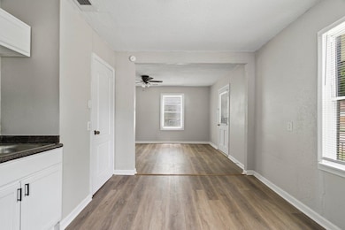 Unfurnished dining area featuring dark wood-style flooring, plenty of natural light, a ceiling fan, and a textured ceiling