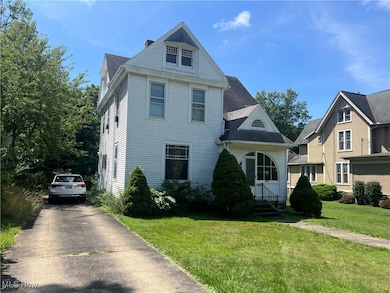 View of front of property featuring a front yard, asphalt driveway, and a shingled roof